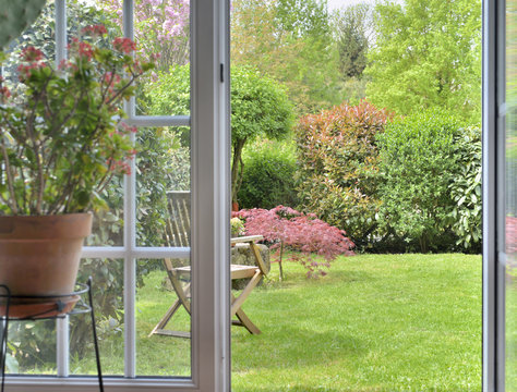 Fototapeta Garden seen by the inside of a house through a door makes windows opened
