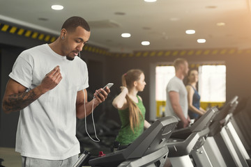 Fototapeta na wymiar Black sporty man on treadmill in fitness club