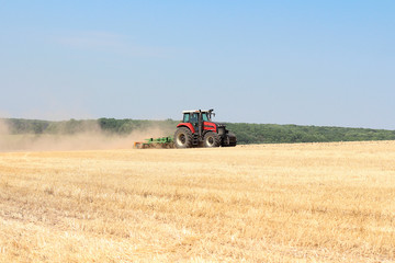 Obraz premium Harvesting wheat on a tractor in summer field. Agriculture