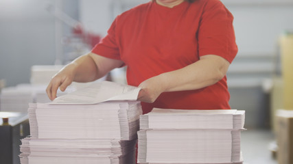 Female worker typography turning pages of a printed magazine