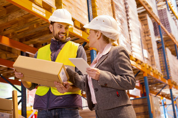 Delivery managing. Nice pleasant woman talking to the delivery man while controlling the delivery service in the warehouse