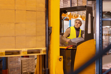 Fototapeta na wymiar Automated process. Professional skilled man wearing special uniform while working with a technical machine in the warehouse