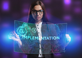 The concept of business, technology, the Internet and the network. A young entrepreneur working on a virtual screen of the future and sees the inscription: Implementation