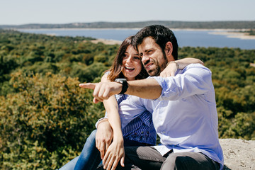 .Young happy couple in love enjoying a nice spring day in the countryside. Located on a hill overlooking a large lake.