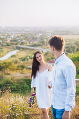 couple standing on the hill hugging and looking on city view from the top of the hill. Young couple in love. Sunny day.