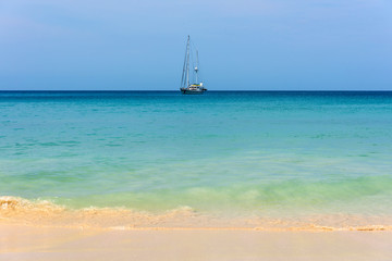 Fototapeta premium Blue sea with sailboat sailing the ocean.