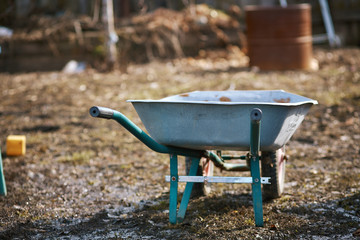 empty garden trolley, wheelbarrow.Old metal trolley on dry grass. Spring in garden. Spring season.cleaning of the garden area, Park. preparation of the garden for planting. Cope space
