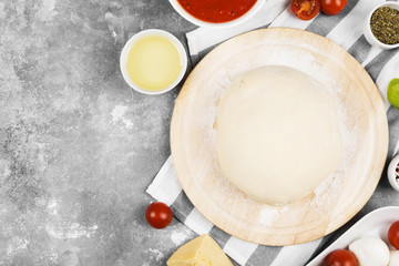 Pizza dough and ingredients for pizza on gray background. Top view, copy space. Food background