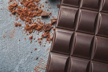 Crushed chocolate bar pieces and cocoa on gray background
