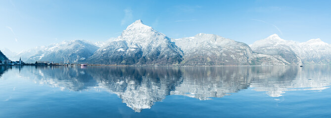 Wide mountain panorama of the Alps in the snow. Grandiose panorama of the snow-capped mountains. Reflections in the water of a mountain lake. Alps in Switzerland. Canton Uri. - obrazy, fototapety, plakaty