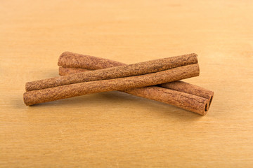 two cinnamon sticks on a wooden background