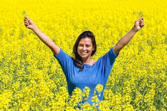 Happy woman arms up in rapeseed field