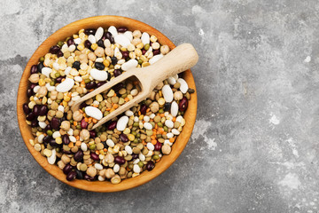 Assortment of beans (red lentil, green lentil, chickpea, peas, red beans, white beans, mix beans, mung bean) on gray background. Top view, copy space. Food background