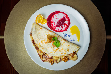 Piadina with bananas, nuts and chocolate paste with a flavor of nuts on a white plate