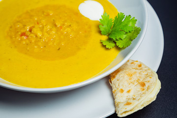 Lentil soup in a ceramic white bowl on a golden background