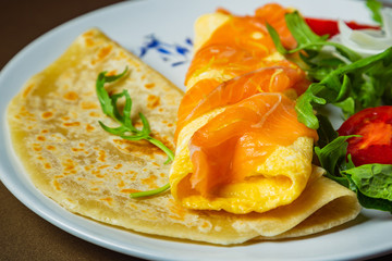 Florentine omelet with salmon, cream cheese and spinach on a white plate