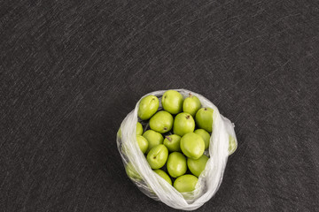 Fresh green apricots in package on black background