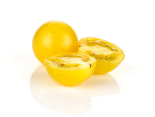 Yellow grape cherry tomatoes one whole and two sliced halves isolated on white background.