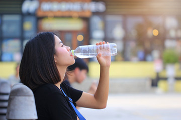 Woman drinking water on street background