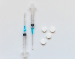 Syringes and pills on a white background.