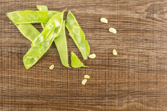 Flat green beans with seeds top view isolated on wooden background.
