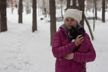 Fototapeta na wymiar A young girl walks with a cat in a winter forest