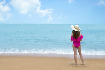 Beautiful woman in pink bikini and straw hat on the sea shore , Relaxed and enjoying tropical beach and summer vacation