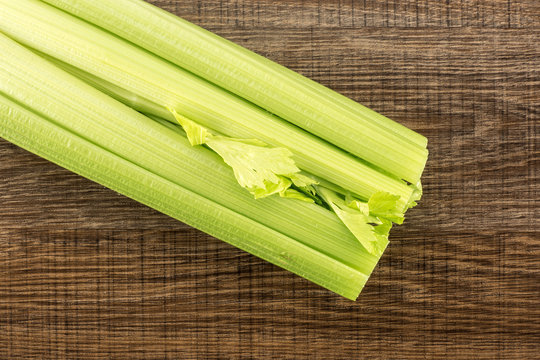 One fresh green celery isolated on wooden background.