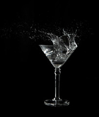 Martini glass low key photo in studio on black background and water plash