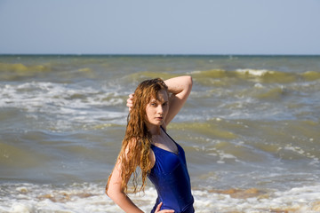 Fototapeta na wymiar A blonde girl in a blue bathing suit on the beach. Beach holidays