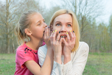 The daughter tells secrets to the mother's ear.