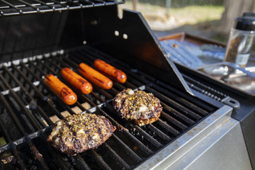 some burgers and hot dogs cooking over an open grill outside - 202204473
