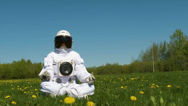 Girl cosmonaut practicing meditation on a flower field