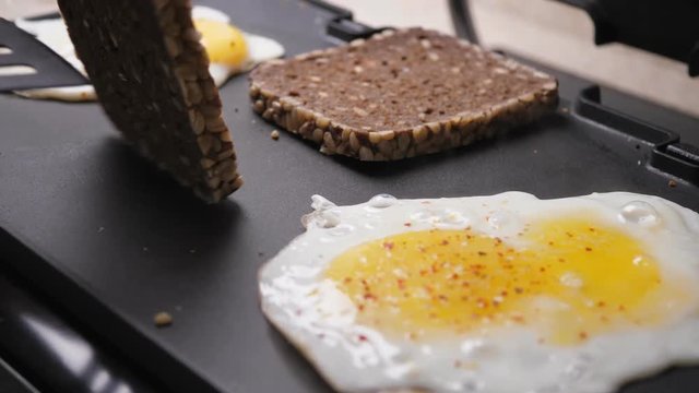 Cooking fried eggs and toasts