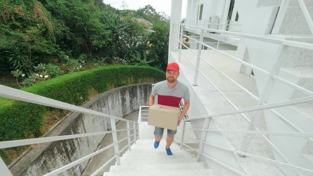 Postman in uniform quickly climbs the stairs to deliver the parcel.