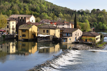 Fototapeta na wymiar Il paesino di Borghetto sul Mincio,si rispecchia tranquillo nelle calme acque del fiume.