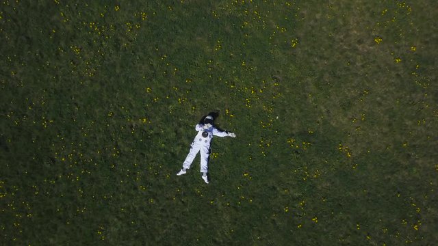 Astronaut lying on the grass looking at the sky