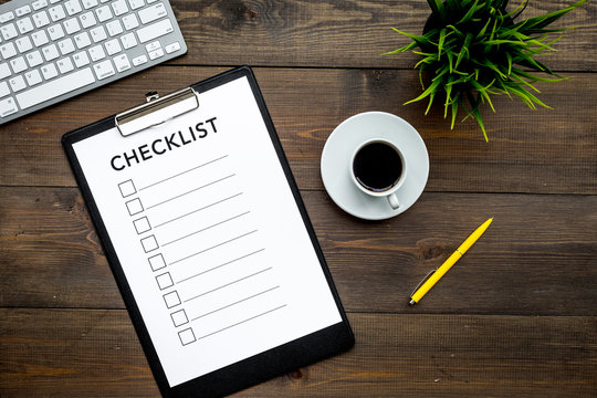 Blank checklist with space for ticks on pad on office desk. Checklist for office worker, manager, businessman, chief on dark wooden background top view