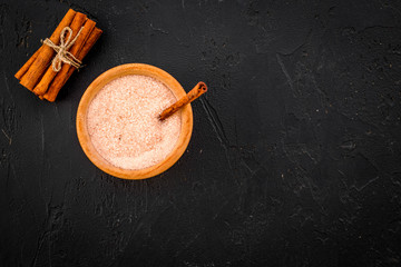 Cinnamon for cooking. Cinnamon sticks near bowl with sugar on black background top view copy space