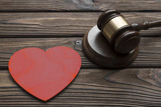 hammer of a judge, a wooden figure of a red heart on a wooden background. family law.