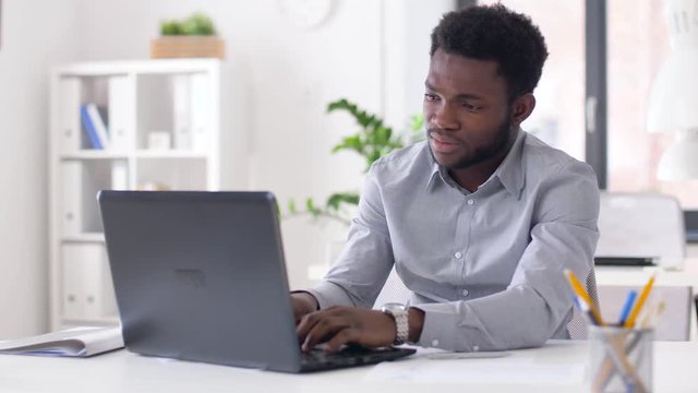 business, people, deadline and technology concept - stressed african american businessman with laptop computer and papers working at office and looking at wristwatch