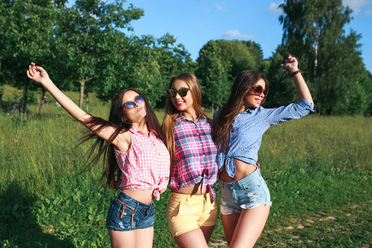 Happy friends in the park on a sunny day . Summer lifestyle portrait of three hipster women enjoy nice day, wearing bright sunglasses. Best friends girls having fun,