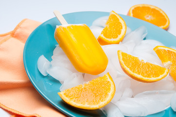 Orange popsicle on a plate of ice cubes