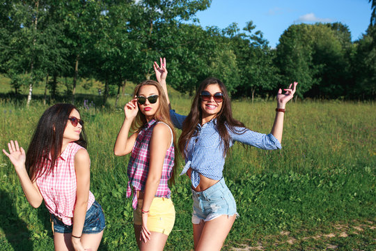 Happy friends in the park on a sunny day . Summer lifestyle portrait of three hipster women enjoy nice day, wearing bright sunglasses. Best friends girls having fun,