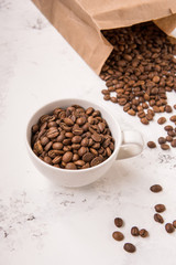 Coffee beans in a cup on a white table