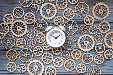 clock alarm clock on gear wheels background on a wooden background. mechanism.