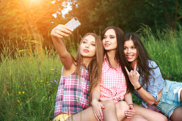 Happy three friends women a selfie on a summers day in park