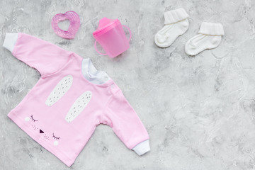Newborn baby's background. Clothes for small girl with booties on grey background top view copy space