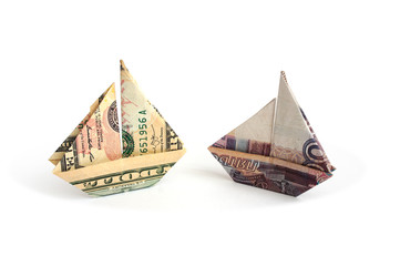  Ruble and dollar bills in the form of sailboats on a white background