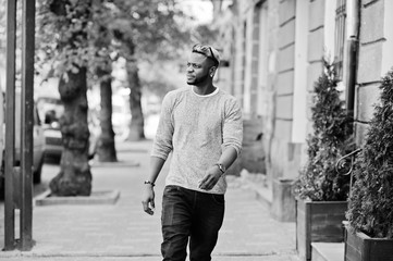 Stylish african american boy on gray sweater and black sunglasses posed on street. Fashionable black guy.